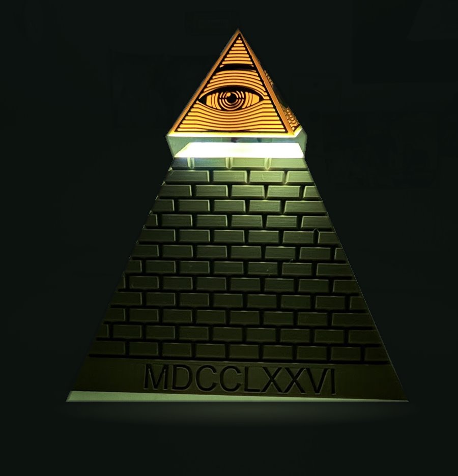 A dark bronze brick pyramid marked MDCCLXXVI with a glowing amber Eye of Providence capstone floating above a band of white light at its top.